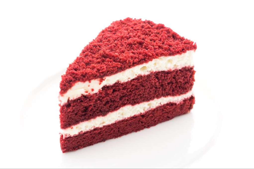 a piece of red velvet cake with white cream on a white backround