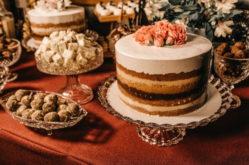 A table full of sweets and a cake with roses on top