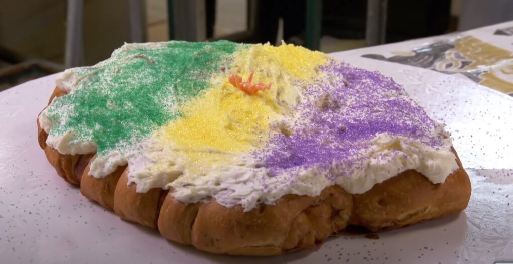a depiction on the king cake with green, yellow and purple on the table
