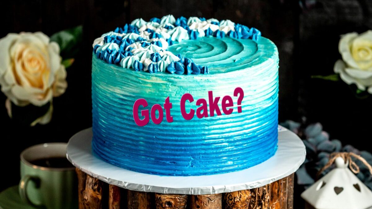 A blue cake with cream with the writing “Got Cake?’ on it