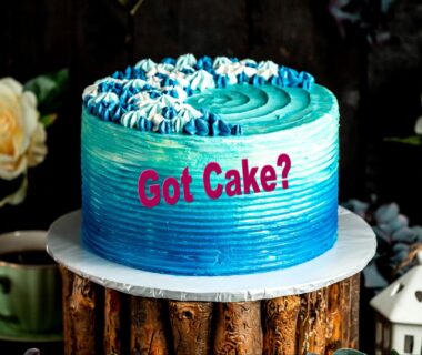 A blue cake with cream with the writing “Got Cake?’ on it
